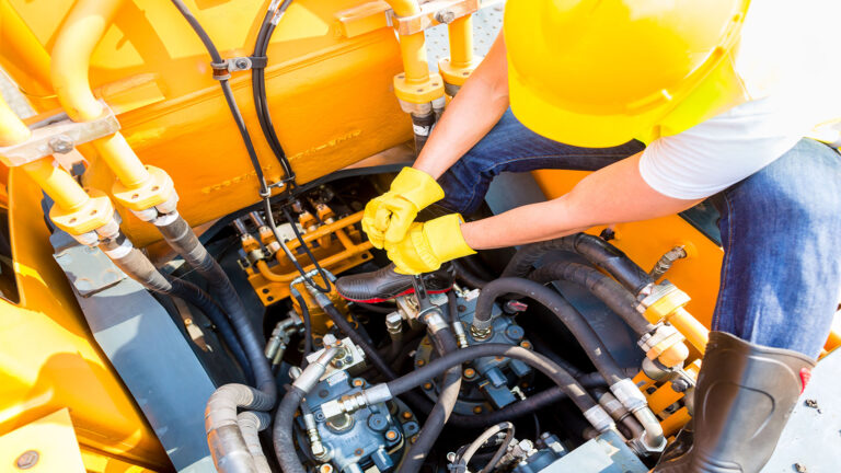 worker maintaining a heavy equipment engine