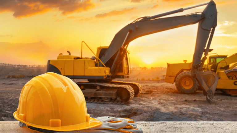 construction hat and gloves sitting on ledge in front of heavy construction machines