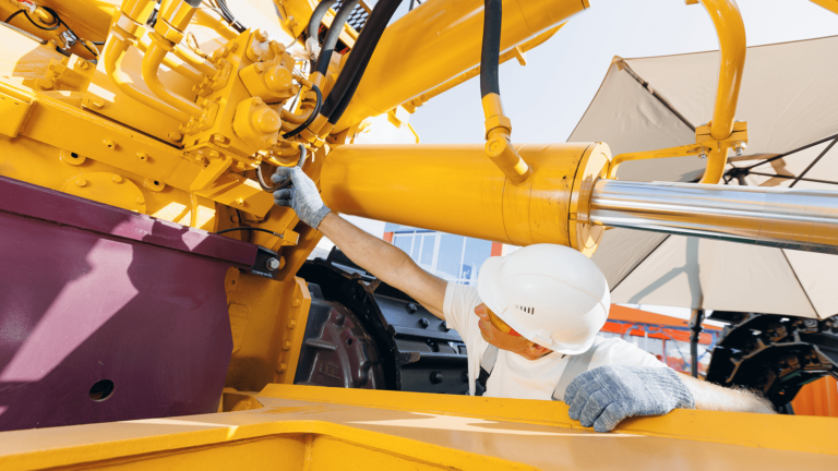 mechanic in hardhat working on hydraulic hose system